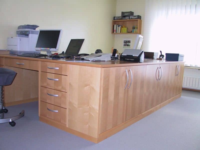 Schreibtisch aus hellem Holz mit Schubkästen in einem Büro